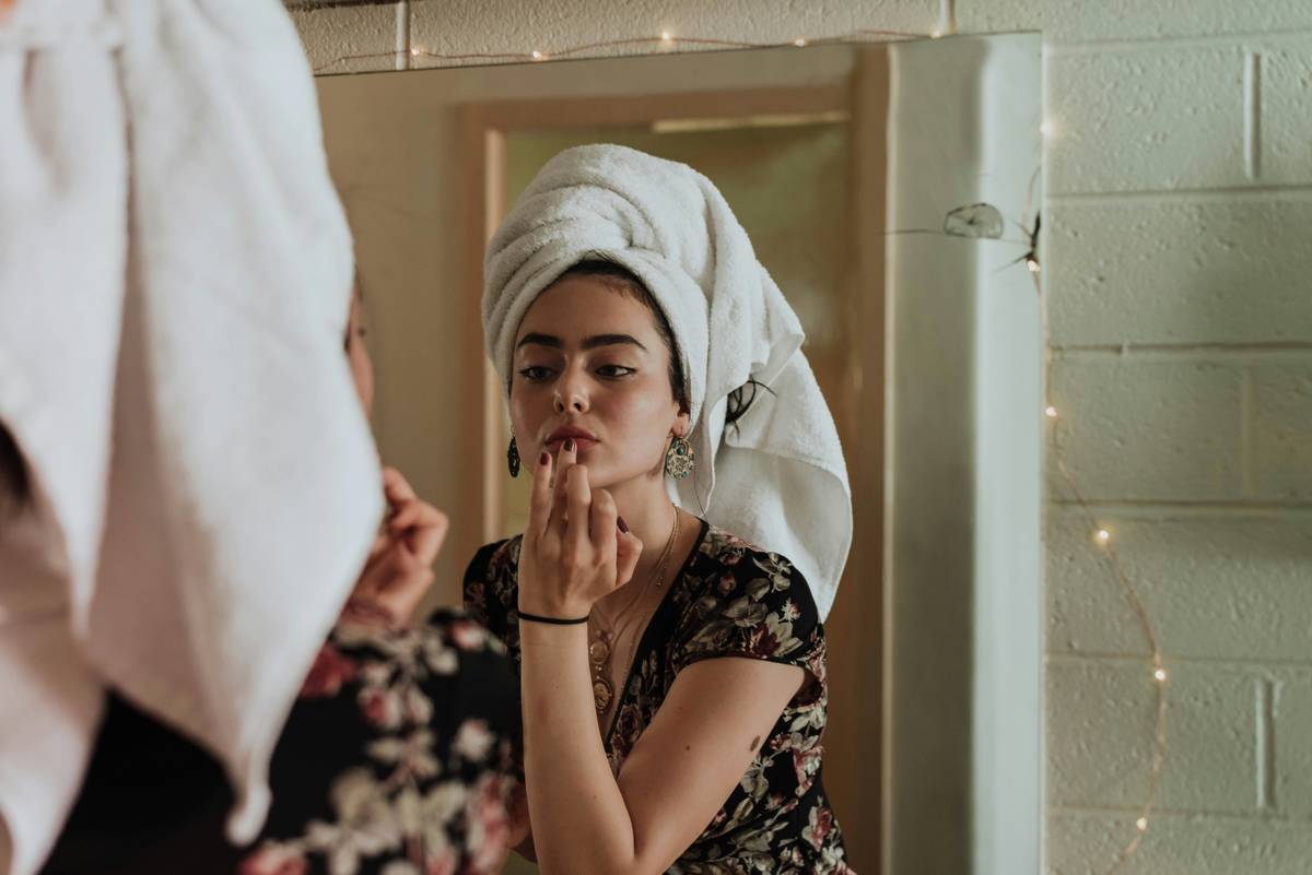 Woman using an application precision mirror with LED lighting for detailed eye makeup application
