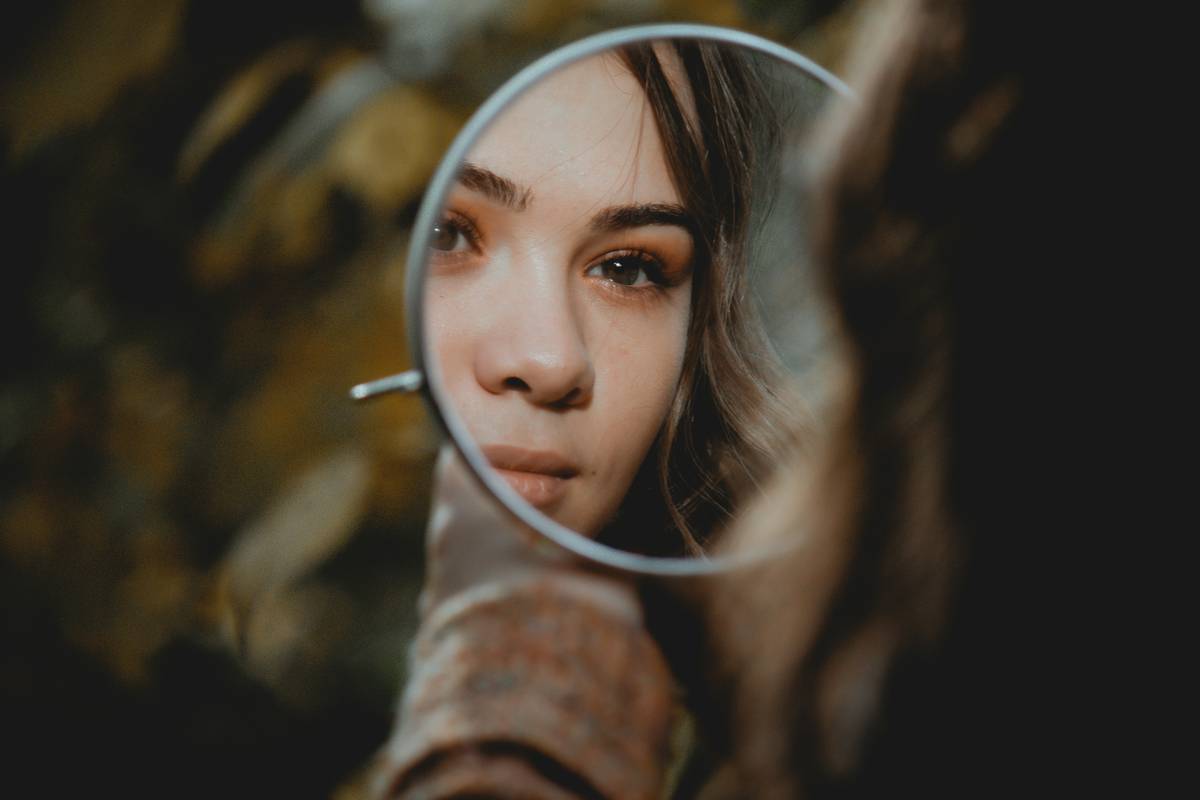 Woman using a makeup enhancing mirror with LED lights for precise eyeliner application